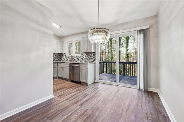 kitchen featuring dishwasher, decorative light fixtures, tasteful backsplash, and light hardwood / wood-style floors