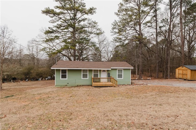 ranch-style house featuring a front yard, a deck, and a storage shed