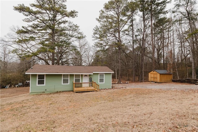 ranch-style home with a front yard, a deck, and a storage unit