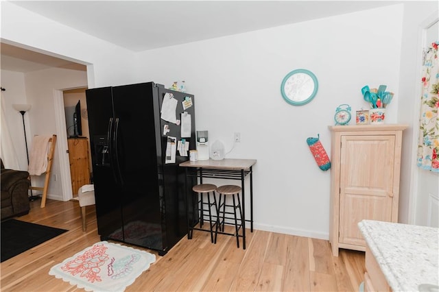 kitchen with light hardwood / wood-style flooring and black fridge with ice dispenser