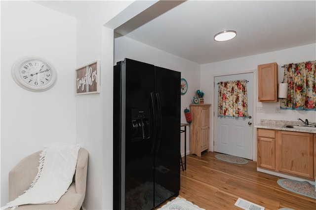 kitchen with sink, light wood-type flooring, and black fridge