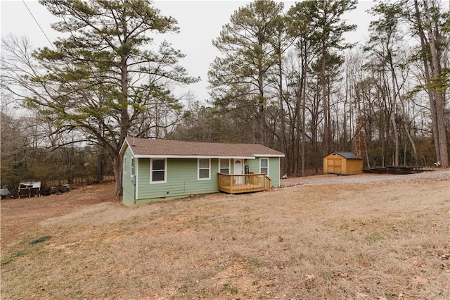 view of front of house featuring a deck, a front yard, and a shed