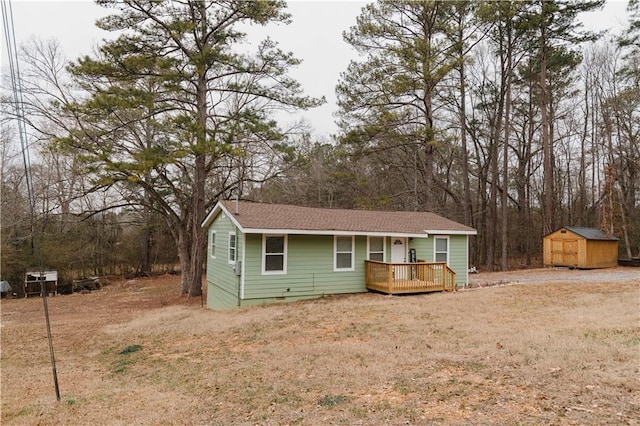 ranch-style house featuring a front yard, a deck, and a shed