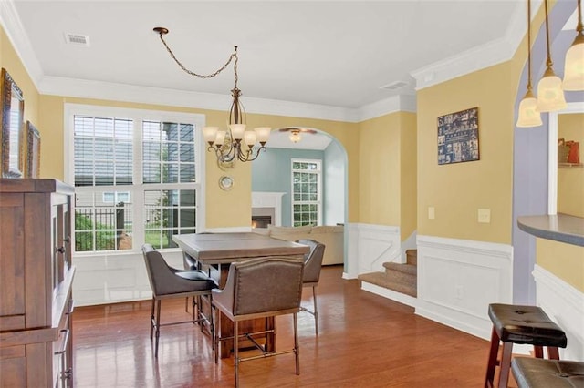 2685 Sardis Chase Ct, Buford, GA 30519 - dining space featuring a lit fireplace, dark wood-style floors, wainscoting, arched walkways, and ornamental molding
