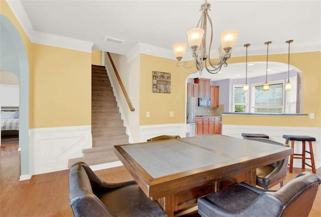 2685 Sardis Chase Ct, Buford, GA 30519 - dining space featuring a wainscoted wall, a chandelier, ornamental molding, stairs, and light wood-style flooring