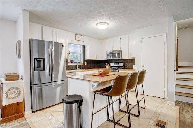 151 Quail Hollow Dr, Dallas, GA 30157 - kitchen featuring appliances with stainless steel finishes, white cabinets, a breakfast bar area, a center island, and decorative backsplash