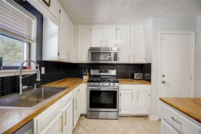 151 Quail Hollow Dr, Dallas, GA 30157 - kitchen with appliances with stainless steel finishes, white cabinetry, light tile patterned floors, backsplash, and a textured ceiling