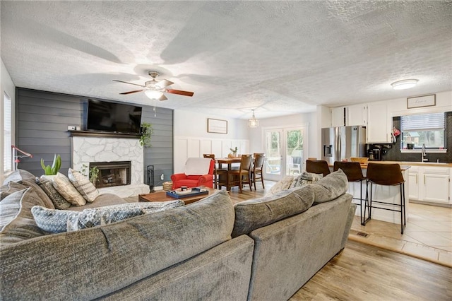 151 Quail Hollow Dr, Dallas, GA 30157 - living room with a textured ceiling, light wood-style floors, a ceiling fan, and a stone fireplace