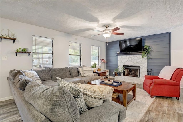 151 Quail Hollow Dr, Dallas, GA 30157 - living area featuring light wood-style floors, a stone fireplace, ceiling fan, and a textured ceiling