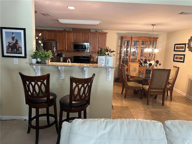 7946 Gossamer, Fairburn, GA 30213 - kitchen featuring stainless steel appliances, a breakfast bar area, brown cabinets, a peninsula, and decorative light fixtures