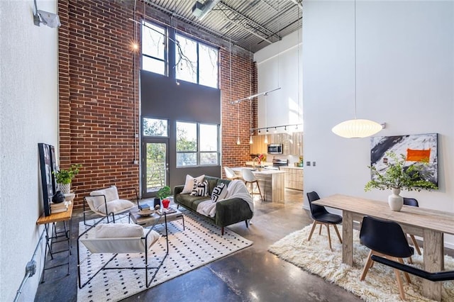 living room with finished concrete floors, brick wall, and a high ceiling