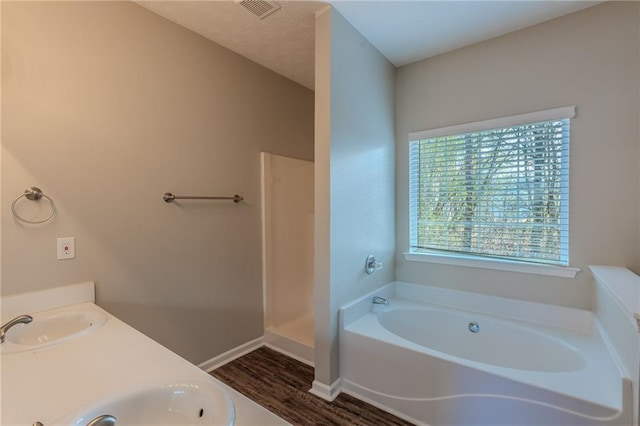 bathroom with a tub to relax in, wood-type flooring, and vanity