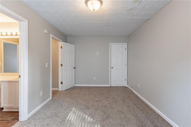 unfurnished bedroom featuring a textured ceiling, carpet flooring, and ensuite bath