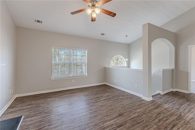 empty room featuring ceiling fan, vaulted ceiling, dark hardwood / wood-style flooring, and a textured ceiling