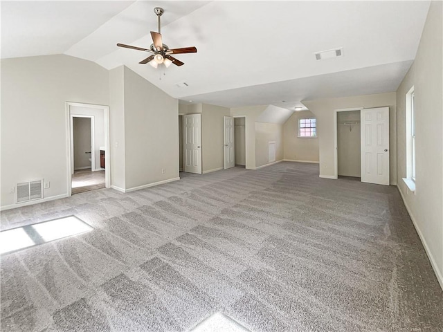 unfurnished living room with ceiling fan, vaulted ceiling, and carpet