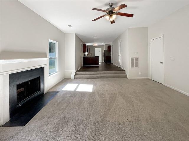 unfurnished living room featuring ceiling fan and dark colored carpet