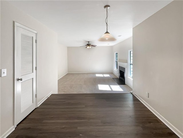 unfurnished living room with dark hardwood / wood-style floors and ceiling fan