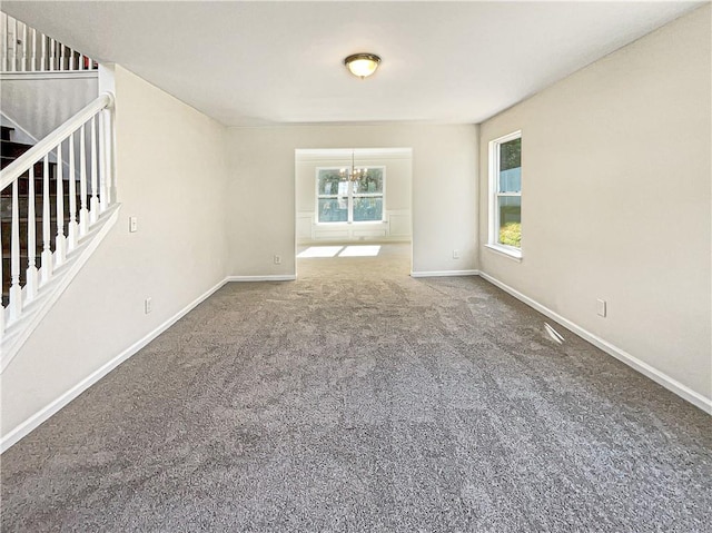 carpeted empty room with an inviting chandelier