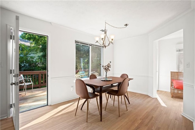 dining room with crown molding, light wood-style floors, baseboards, and a chandelier