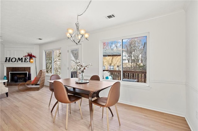 dining space featuring visible vents, baseboards, light wood-style floors, and a fireplace