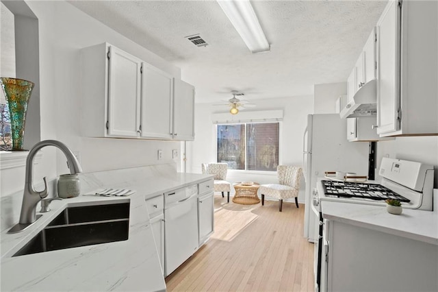 kitchen with visible vents, under cabinet range hood, a sink, white appliances, and light wood finished floors