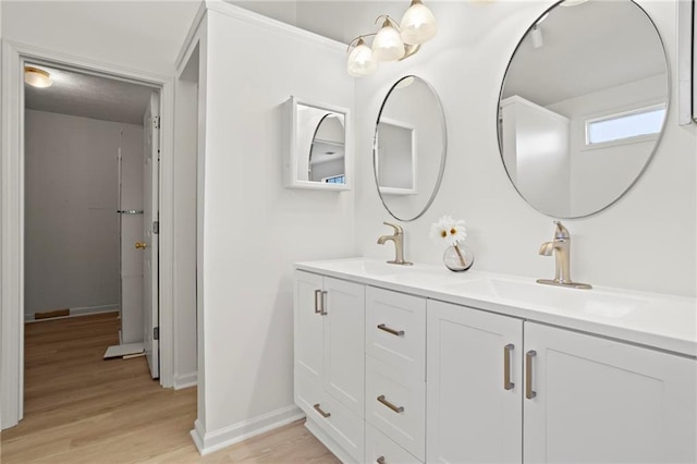 full bathroom featuring double vanity, wood finished floors, baseboards, and a sink