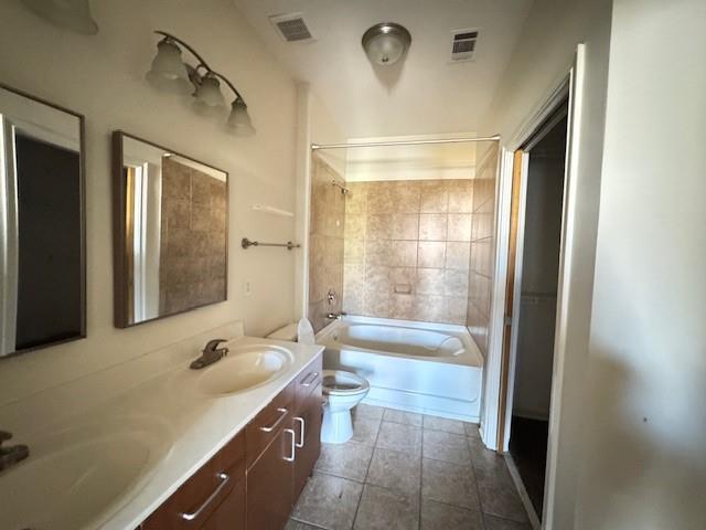 full bath with visible vents, a sink, toilet, and double vanity