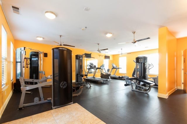 exercise room with baseboards, visible vents, and a ceiling fan