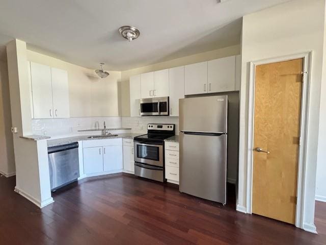 kitchen with tasteful backsplash, white cabinetry, stainless steel appliances, and dark wood-style flooring