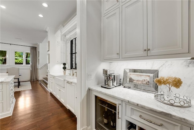 bar with light stone counters, tasteful backsplash, and white cabinets