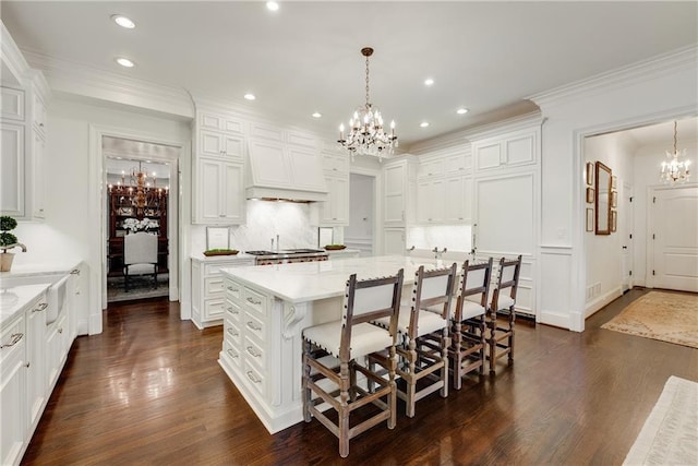 kitchen with a spacious island, a chandelier, hanging light fixtures, a kitchen breakfast bar, and custom range hood