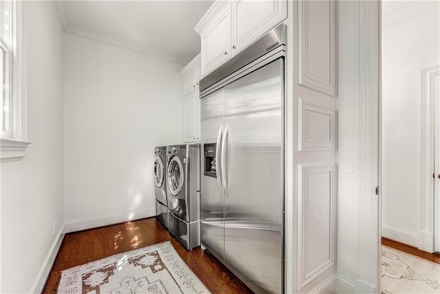 washroom featuring cabinets, washing machine and clothes dryer, crown molding, and dark wood-type flooring