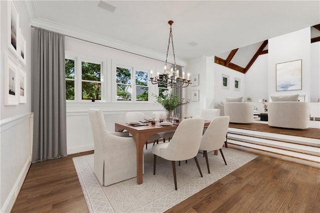 dining area featuring dark wood-type flooring, ornamental molding, a chandelier, and vaulted ceiling