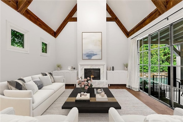 living room featuring beamed ceiling, wood-type flooring, a fireplace, and high vaulted ceiling