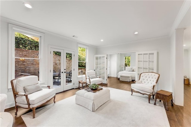 living area with wood-type flooring, ornamental molding, and french doors