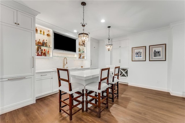 dining room featuring hardwood / wood-style flooring, ornamental molding, and indoor wet bar