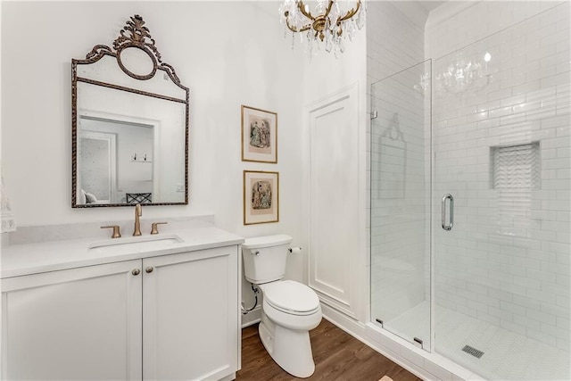 bathroom featuring wood-type flooring, a chandelier, vanity, an enclosed shower, and toilet