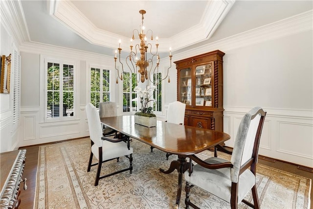 dining room with an inviting chandelier, ornamental molding, a tray ceiling, and hardwood / wood-style floors