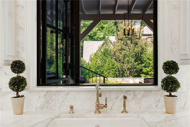 room details featuring sink, a notable chandelier, and light stone counters