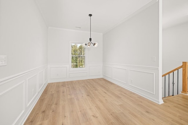 4400 Ross Estates Ct, Snellville, GA 30039 - unfurnished dining area with crown molding, a chandelier, wainscoting, light wood-type flooring, and a decorative wall