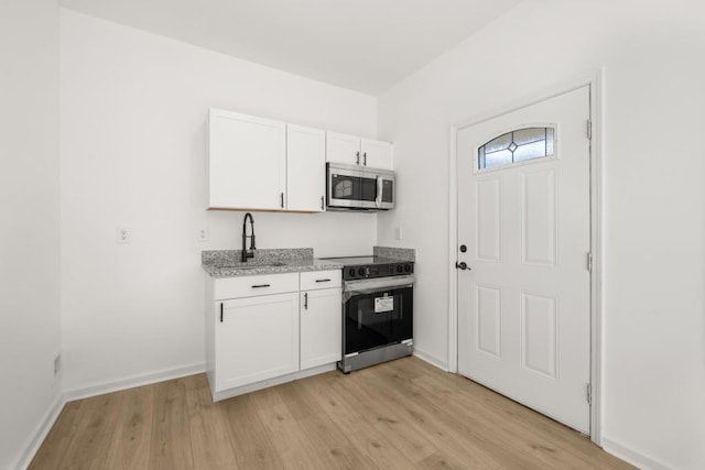 4400 Ross Estates Ct, Snellville, GA 30039 - kitchen with electric stove, stainless steel microwave, a sink, light wood-style flooring, and white cabinets