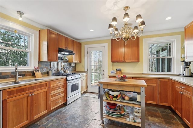 kitchen with stainless steel gas range, a sink, under cabinet range hood, and stone tile floors