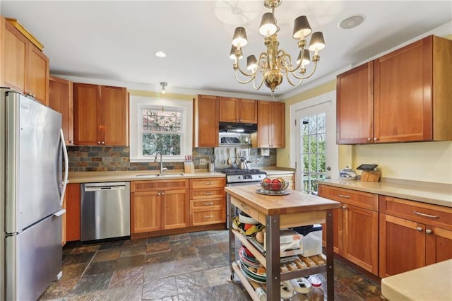 kitchen with stainless steel appliances, stone finish floor, light countertops, and a sink