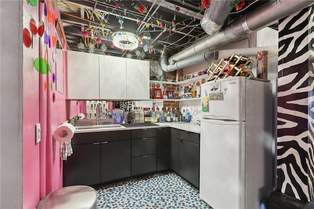 kitchen with tile patterned floors, freestanding refrigerator, light countertops, open shelves, and a sink