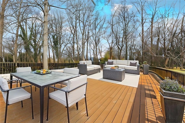 wooden terrace featuring outdoor dining area, fence, and an outdoor hangout area