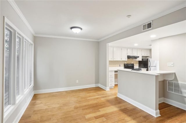 kitchen with under cabinet range hood, visible vents, light countertops, freestanding refrigerator, and electric range oven