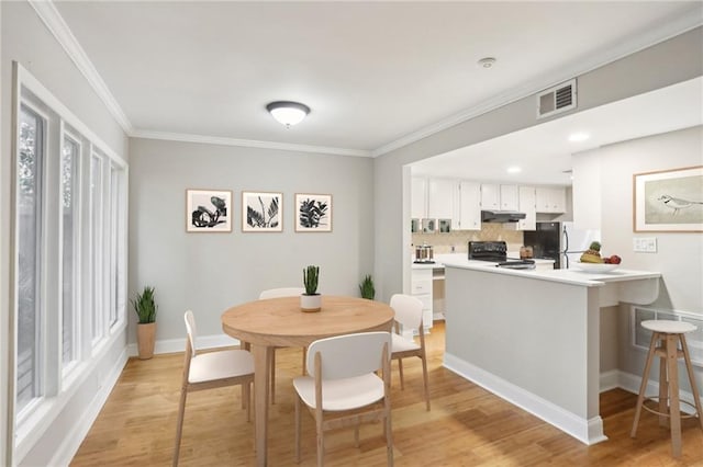 dining room with light wood-style flooring, visible vents, ornamental molding, and baseboards