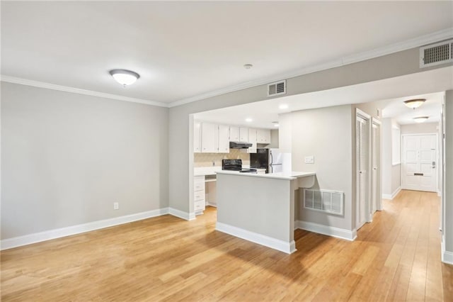 kitchen featuring under cabinet range hood, visible vents, black range with electric stovetop, and freestanding refrigerator