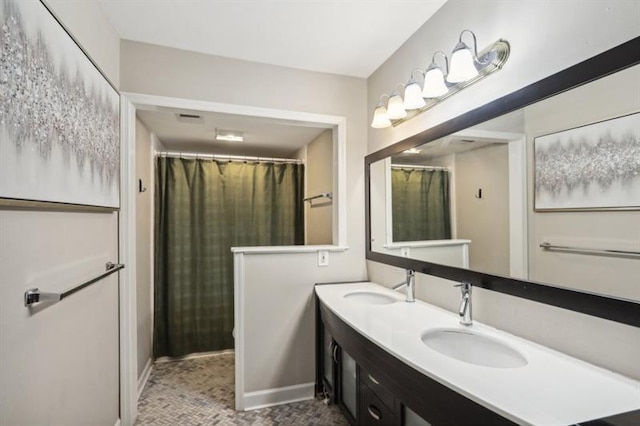 bathroom featuring double vanity, a sink, visible vents, and baseboards