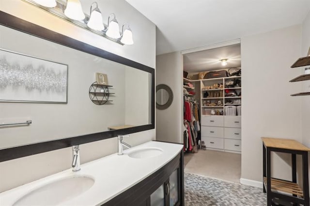 full bath with double vanity, a spacious closet, and a sink